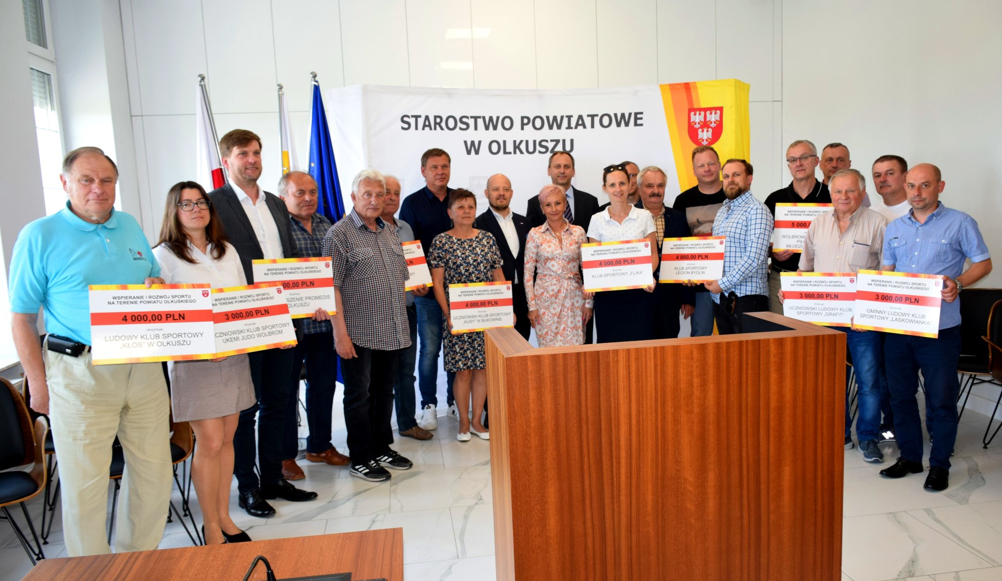 Przedstawiciele Powiatu Olkuskiego oraz przedstawiciele klubów sportowych, które otrzymały dotacje trzymający symboliczne czeki