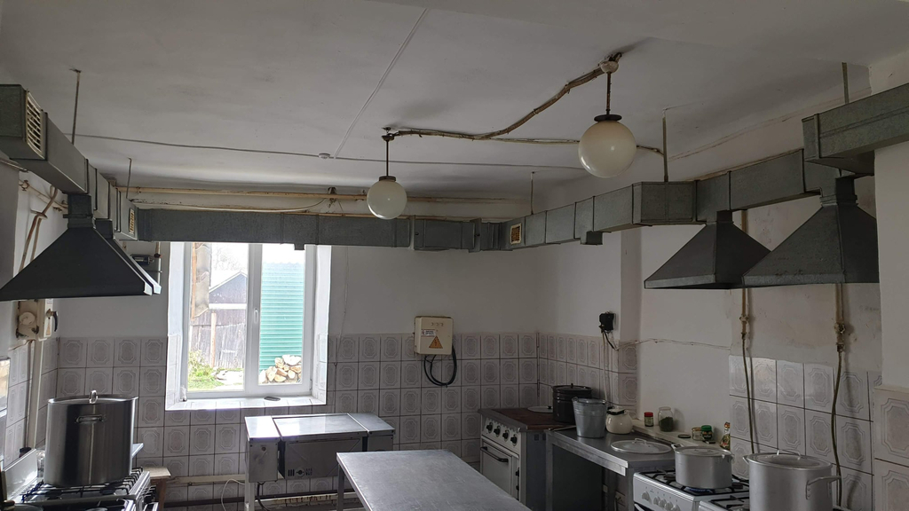 Zdjęcie kuchni, widok na okno blat roboczy, garnki  i kuchenkę